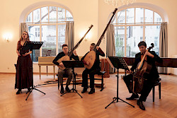 Musiker musizieren auf der Bühne, darunter eine Sängerin, zwei Männer mit Lauten und ein Mann am Cello
